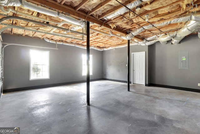 basement featuring a garage, electric panel, and baseboards