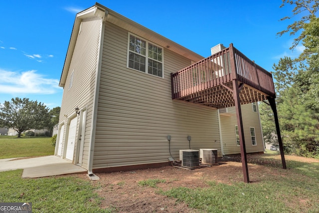 rear view of house featuring a yard, concrete driveway, central AC, a deck, and a garage