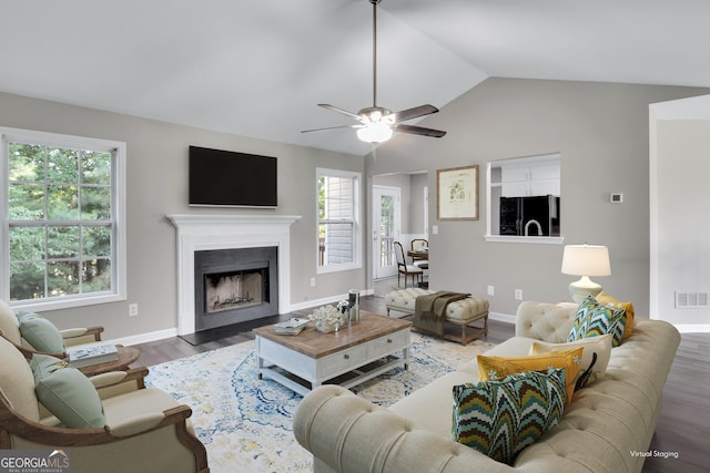 living room featuring lofted ceiling, a fireplace, wood finished floors, and a healthy amount of sunlight