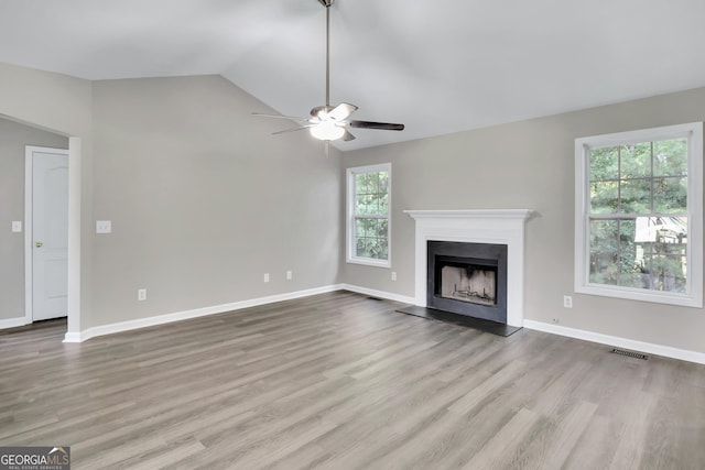 unfurnished living room featuring a fireplace with raised hearth, wood finished floors, visible vents, and lofted ceiling