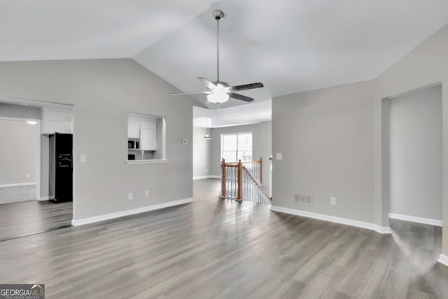 unfurnished living room featuring lofted ceiling, visible vents, baseboards, and wood finished floors