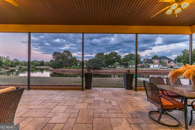 unfurnished sunroom featuring ceiling fan and a water view