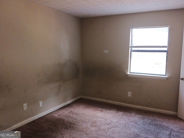 carpeted spare room with a textured ceiling