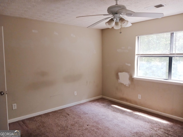 empty room with a textured ceiling, ceiling fan, and carpet