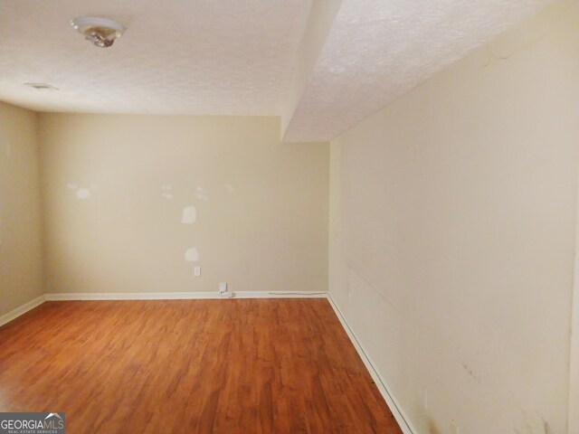 unfurnished room featuring a textured ceiling and hardwood / wood-style flooring