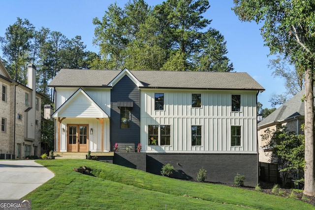 modern inspired farmhouse with french doors, a front yard, board and batten siding, and a shingled roof