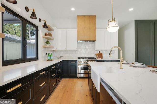 kitchen featuring light wood-style flooring, high end stainless steel range, backsplash, white cabinetry, and light stone countertops