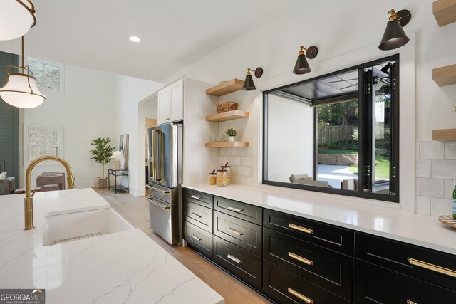 kitchen with light stone countertops, decorative backsplash, high end refrigerator, and hanging light fixtures