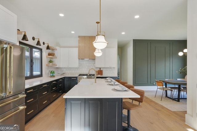 kitchen featuring white cabinets, a breakfast bar area, tasteful backsplash, and high end refrigerator