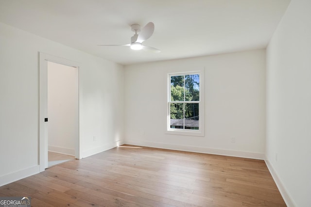 spare room featuring baseboards, light wood finished floors, and ceiling fan