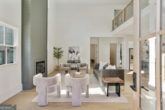 living room with a large fireplace, a high ceiling, and light hardwood / wood-style flooring