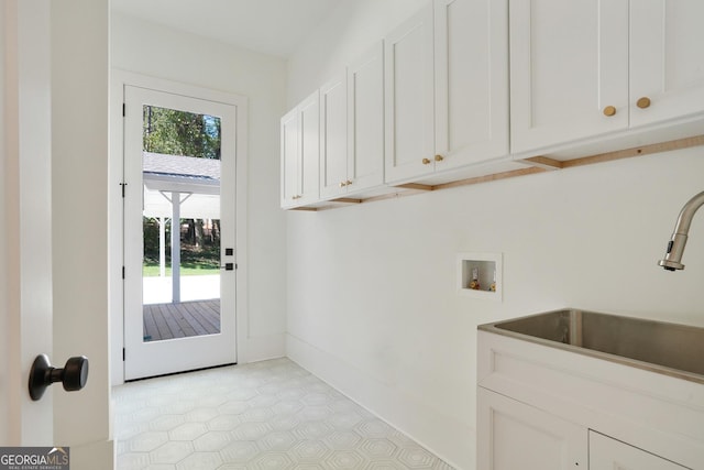 clothes washing area featuring a sink, baseboards, cabinet space, and hookup for a washing machine