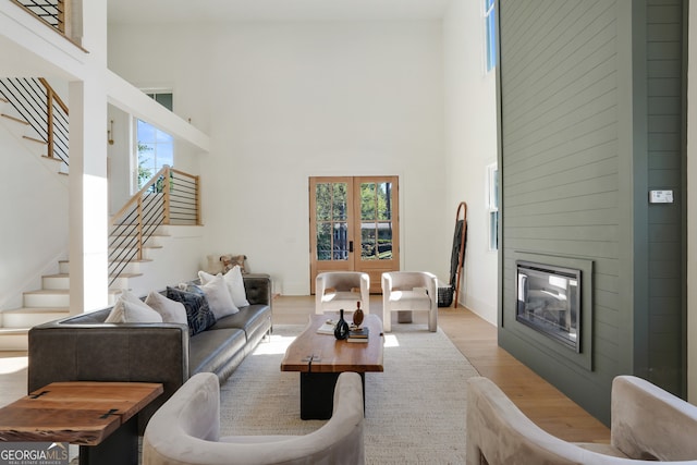 living room with a large fireplace, a healthy amount of sunlight, a high ceiling, and light hardwood / wood-style flooring