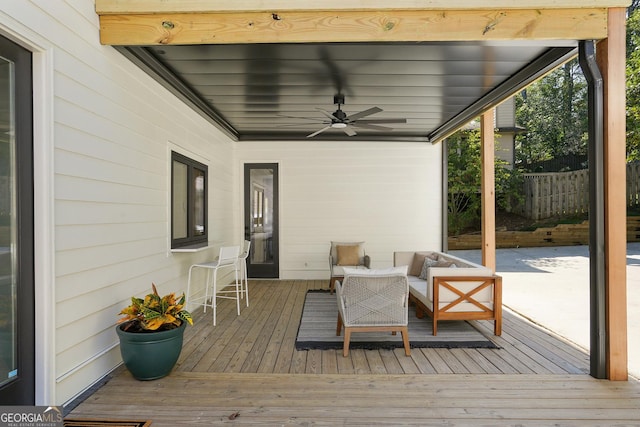 wooden terrace with outdoor lounge area, fence, and ceiling fan