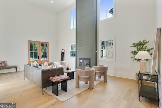 living room with a large fireplace, plenty of natural light, light hardwood / wood-style floors, and a high ceiling