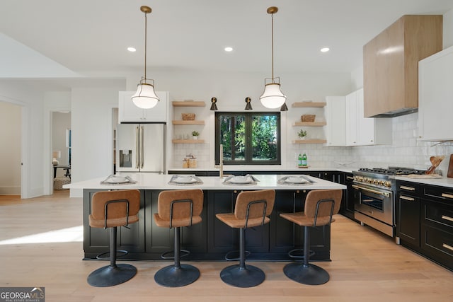 kitchen featuring decorative light fixtures, stainless steel appliances, and a center island with sink