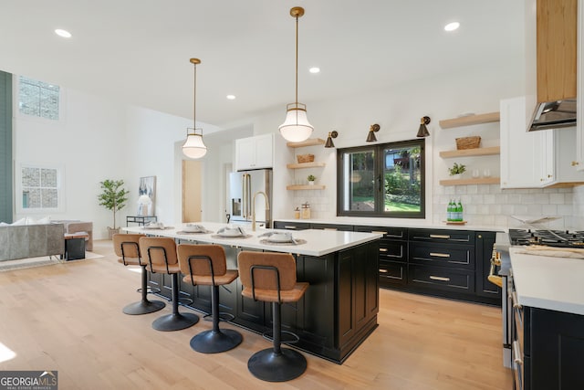 kitchen featuring white cabinets, decorative light fixtures, a healthy amount of sunlight, and a center island with sink