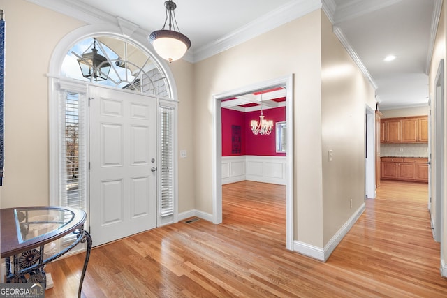 foyer with light hardwood / wood-style flooring, crown molding, and a chandelier