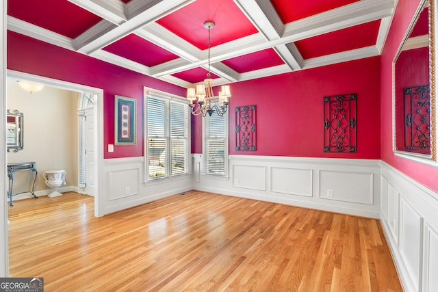 unfurnished dining area with beam ceiling, wood-type flooring, ornamental molding, and coffered ceiling