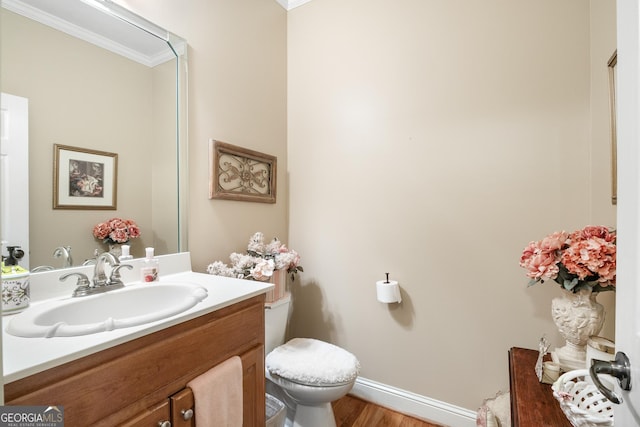 bathroom with wood-type flooring, vanity, toilet, and ornamental molding