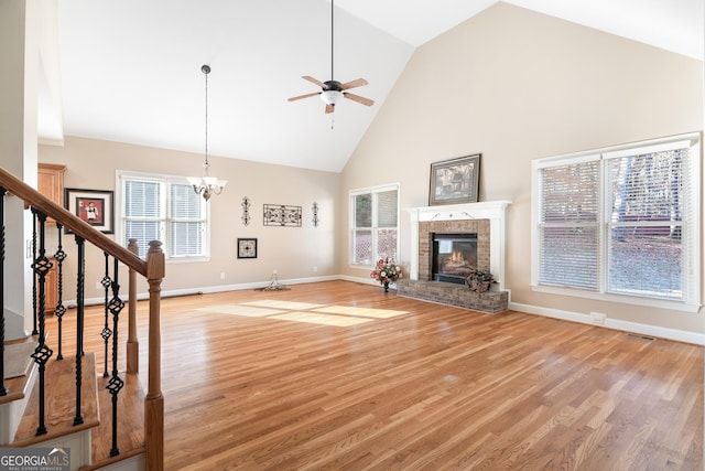 unfurnished living room with a fireplace, high vaulted ceiling, a healthy amount of sunlight, and light wood-type flooring