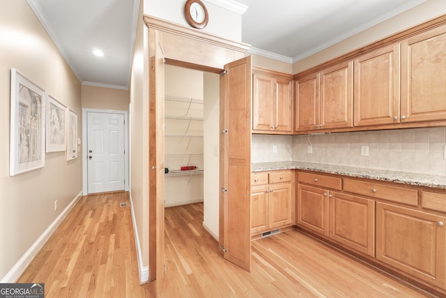 kitchen featuring decorative backsplash, light stone counters, light wood-type flooring, and ornamental molding