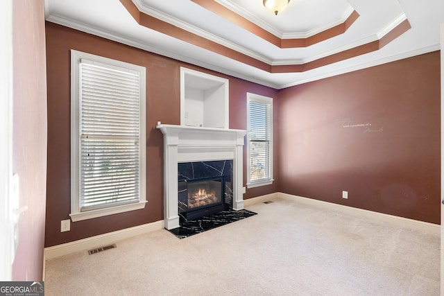 carpeted living room featuring a fireplace, a raised ceiling, and crown molding