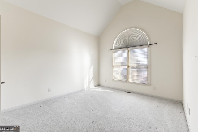 carpeted spare room featuring vaulted ceiling