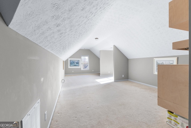 additional living space featuring a textured ceiling, light colored carpet, and lofted ceiling