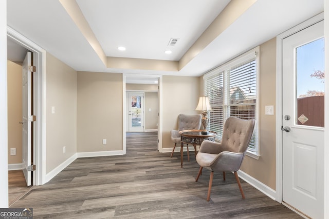 sitting room with a tray ceiling and dark hardwood / wood-style floors