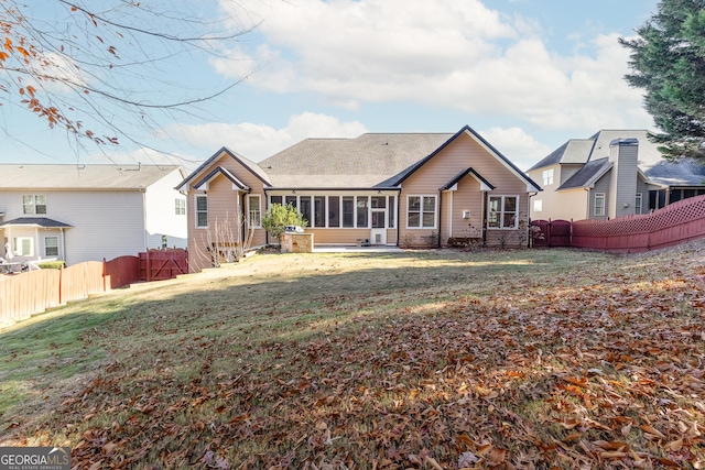 rear view of property featuring a sunroom and a lawn