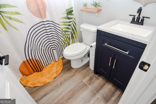 bathroom featuring walk in shower, vanity, toilet, and hardwood / wood-style flooring