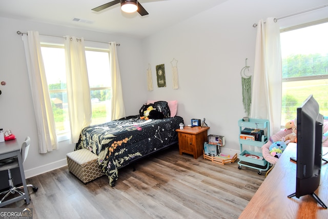 bedroom featuring ceiling fan, hardwood / wood-style floors, and multiple windows