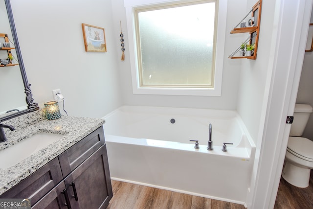 bathroom featuring wood-type flooring, toilet, a bathing tub, and vanity