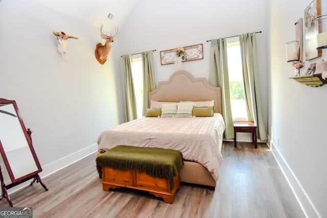 bedroom featuring high vaulted ceiling and hardwood / wood-style flooring