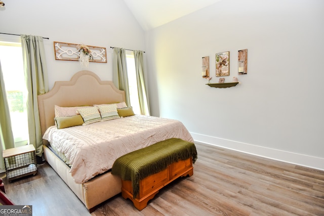 bedroom featuring high vaulted ceiling, hardwood / wood-style floors, and multiple windows