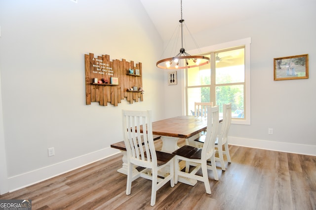 dining space with hardwood / wood-style floors, high vaulted ceiling, and a chandelier