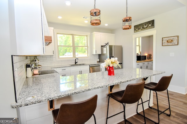 kitchen featuring light hardwood / wood-style floors, stainless steel appliances, white cabinets, and tasteful backsplash