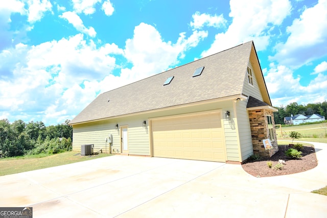 view of side of home with a garage and central air condition unit