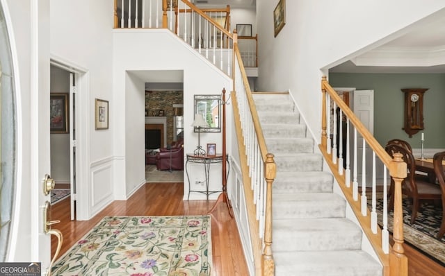 stairway with a tray ceiling, ornamental molding, wood-type flooring, and a towering ceiling