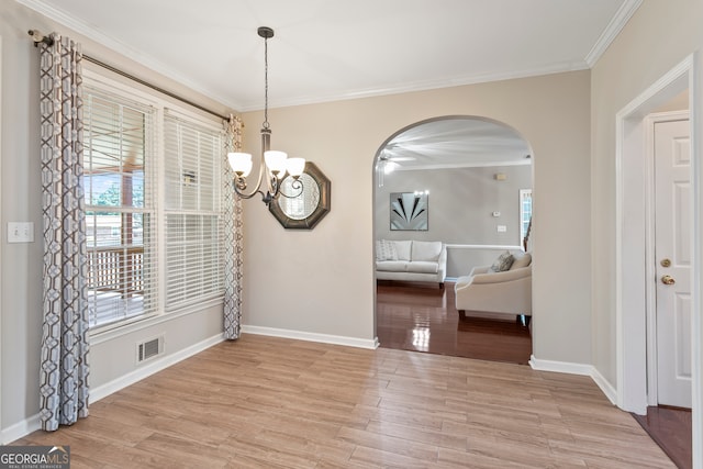 unfurnished dining area featuring crown molding, a notable chandelier, and light hardwood / wood-style floors