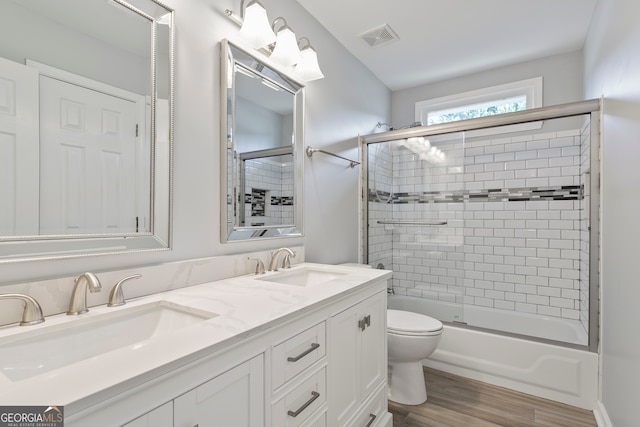 full bathroom with vanity, toilet, hardwood / wood-style floors, and enclosed tub / shower combo