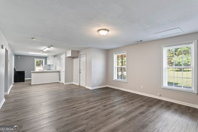 unfurnished living room featuring dark hardwood / wood-style floors, a textured ceiling, and a healthy amount of sunlight