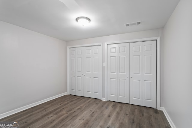 unfurnished bedroom featuring dark hardwood / wood-style floors and two closets