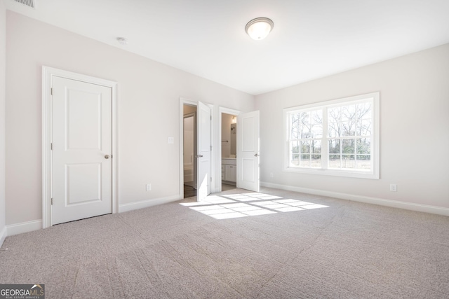 unfurnished bedroom with carpet floors, connected bathroom, and baseboards