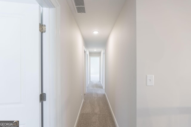 hallway featuring baseboards, visible vents, and carpet flooring