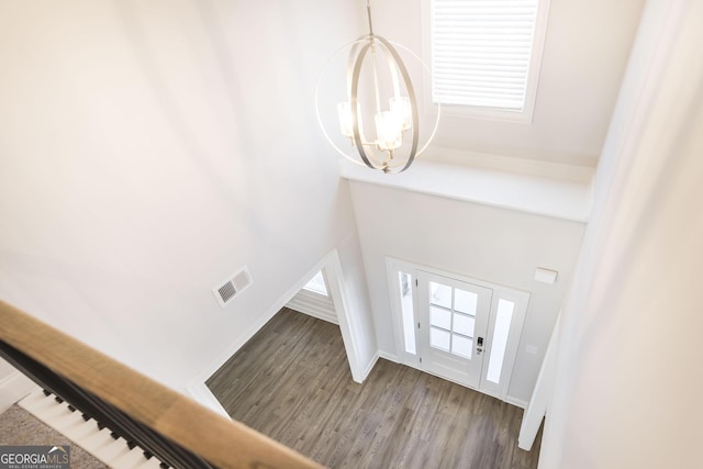 entryway with a chandelier, wood finished floors, visible vents, and baseboards