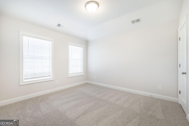 carpeted spare room featuring baseboards and visible vents