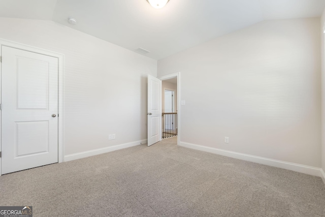 unfurnished bedroom with lofted ceiling, light colored carpet, and baseboards