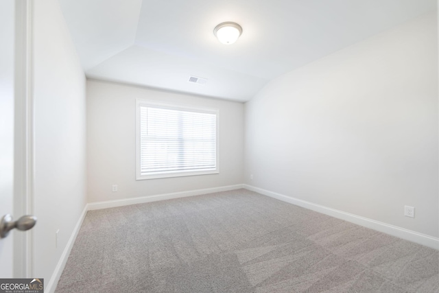 carpeted spare room with lofted ceiling, baseboards, and visible vents